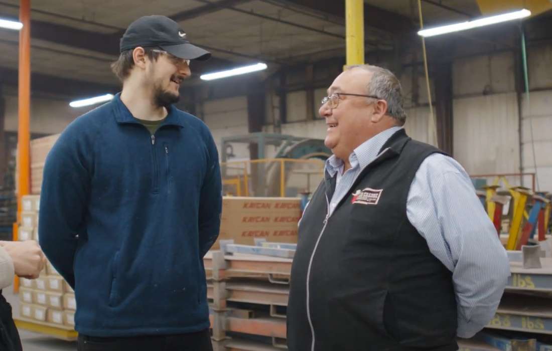 Two individuals talking in a warehouse.